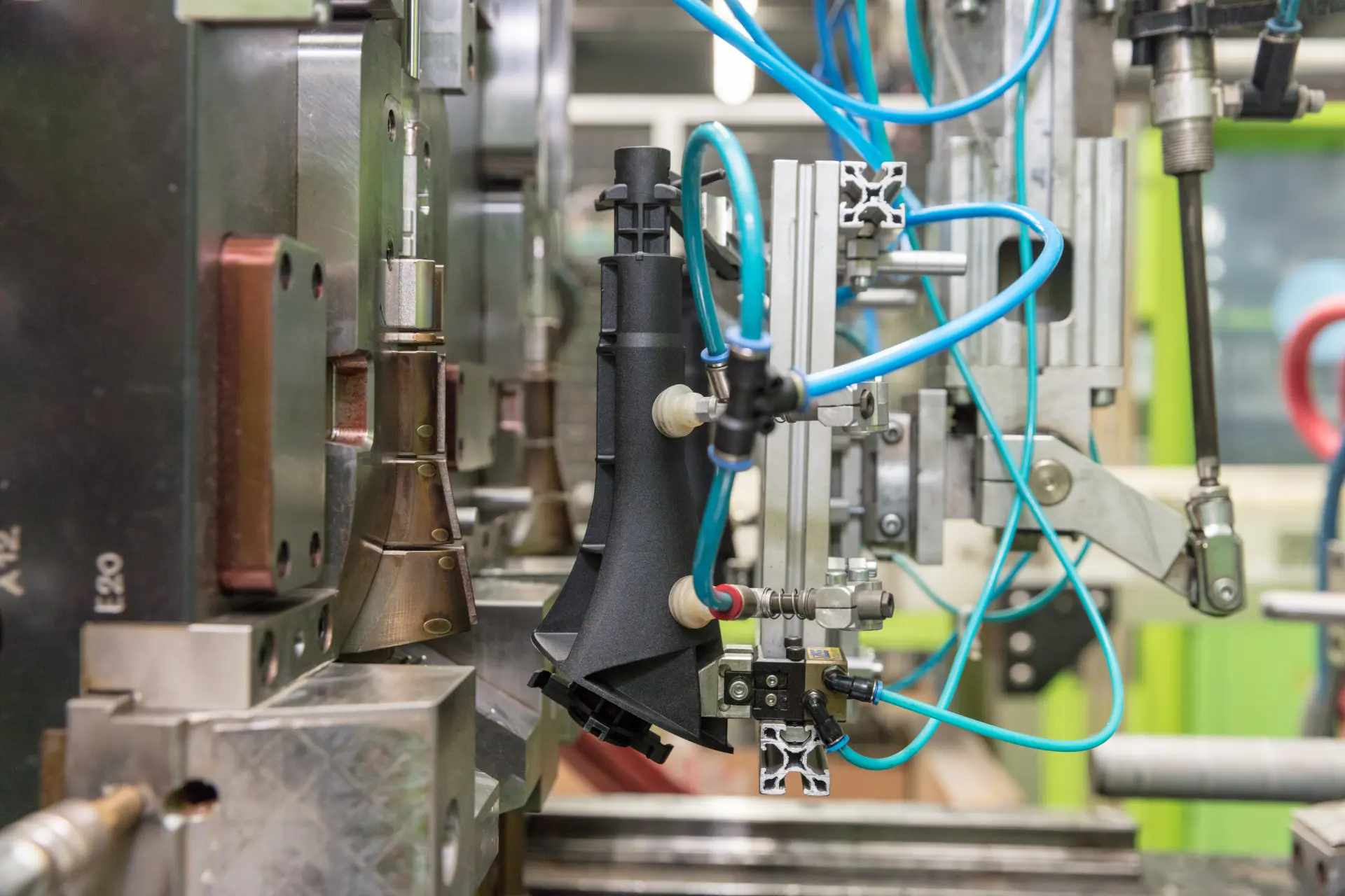 Pneumatic fixture processing a black plastic part in production.